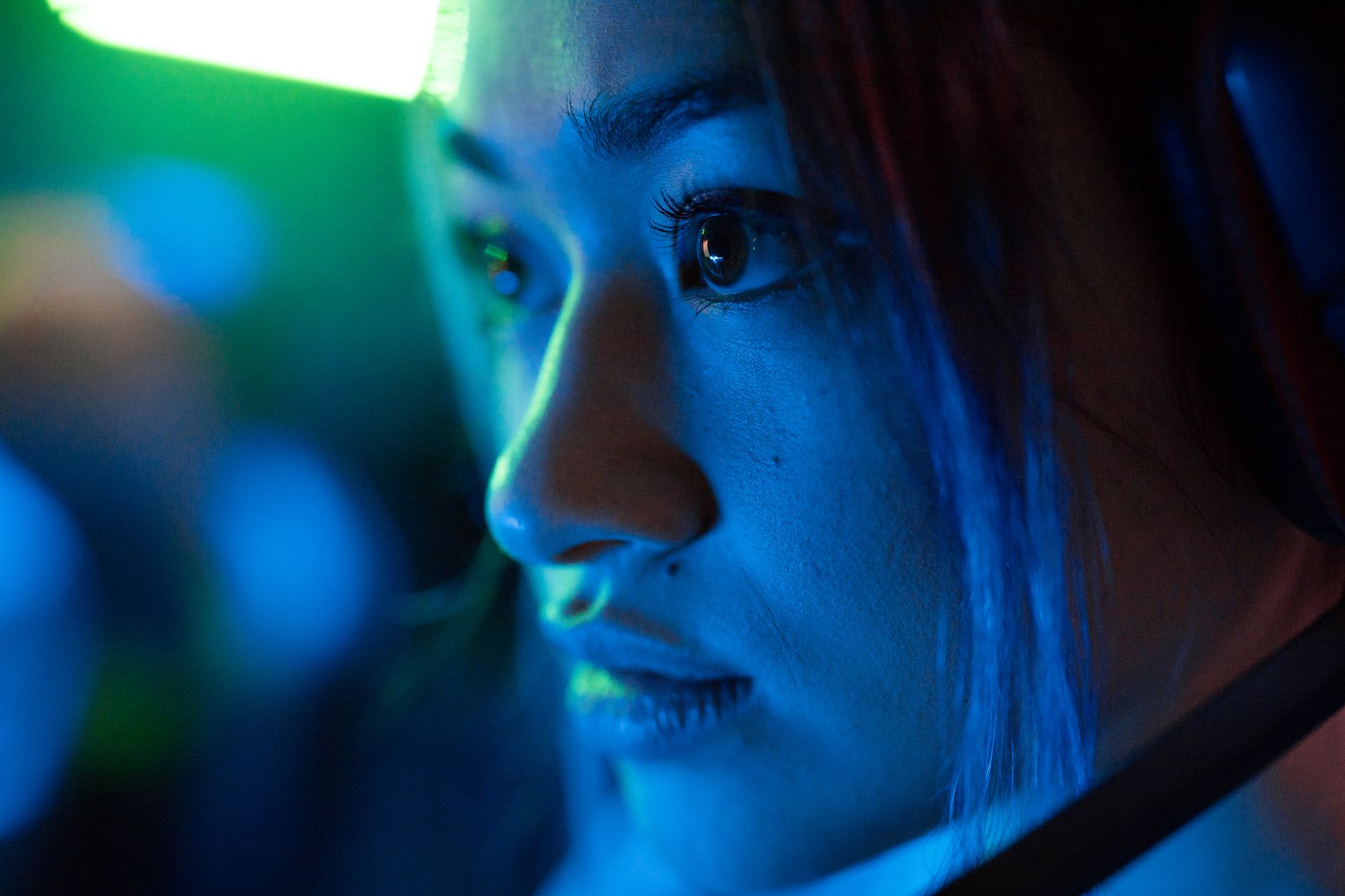 Close-up of a person's face during a video call with unusual lighting and screen artifacts.