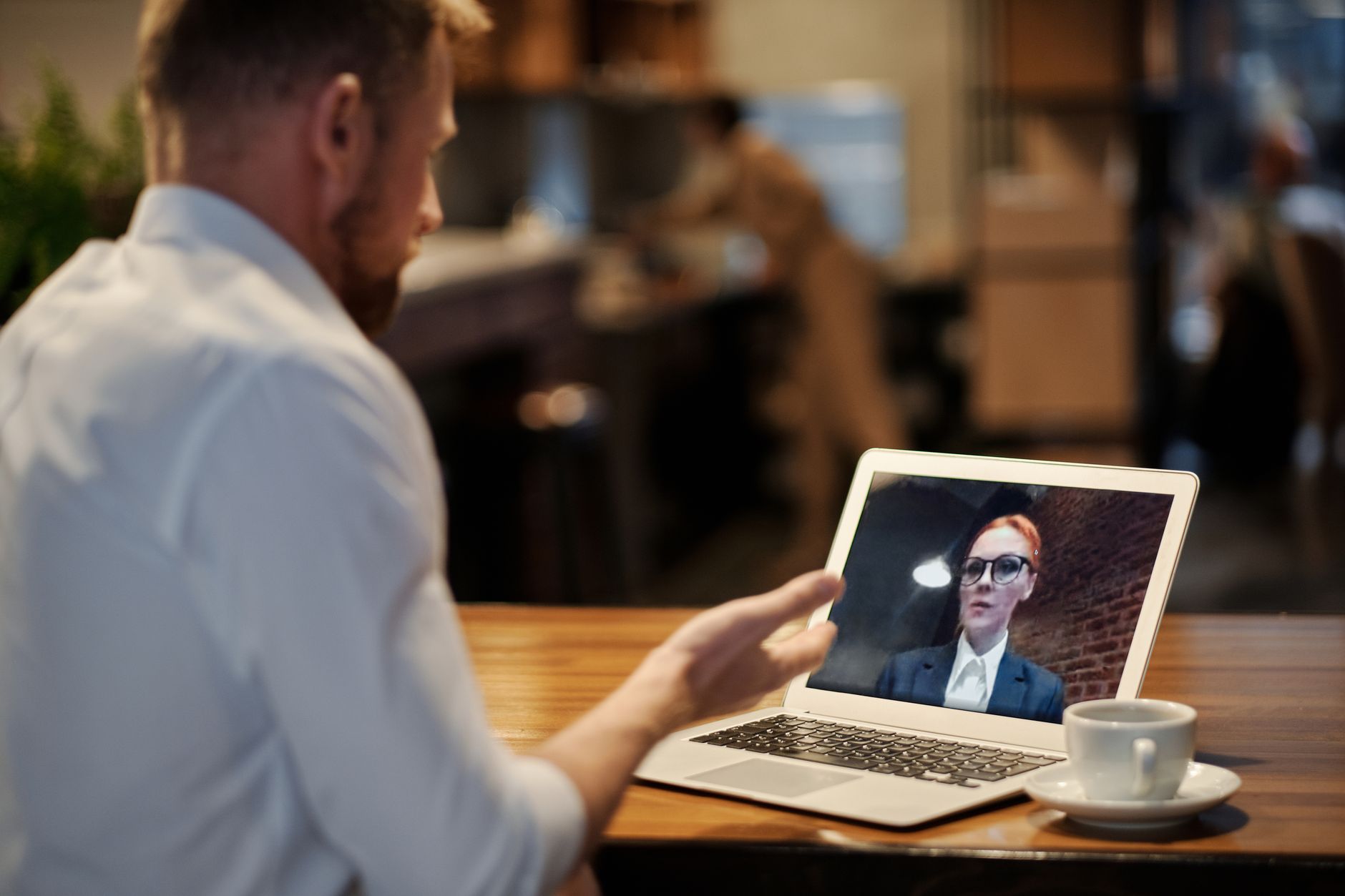 A person on a video call with a skeptical expression while looking at a laptop