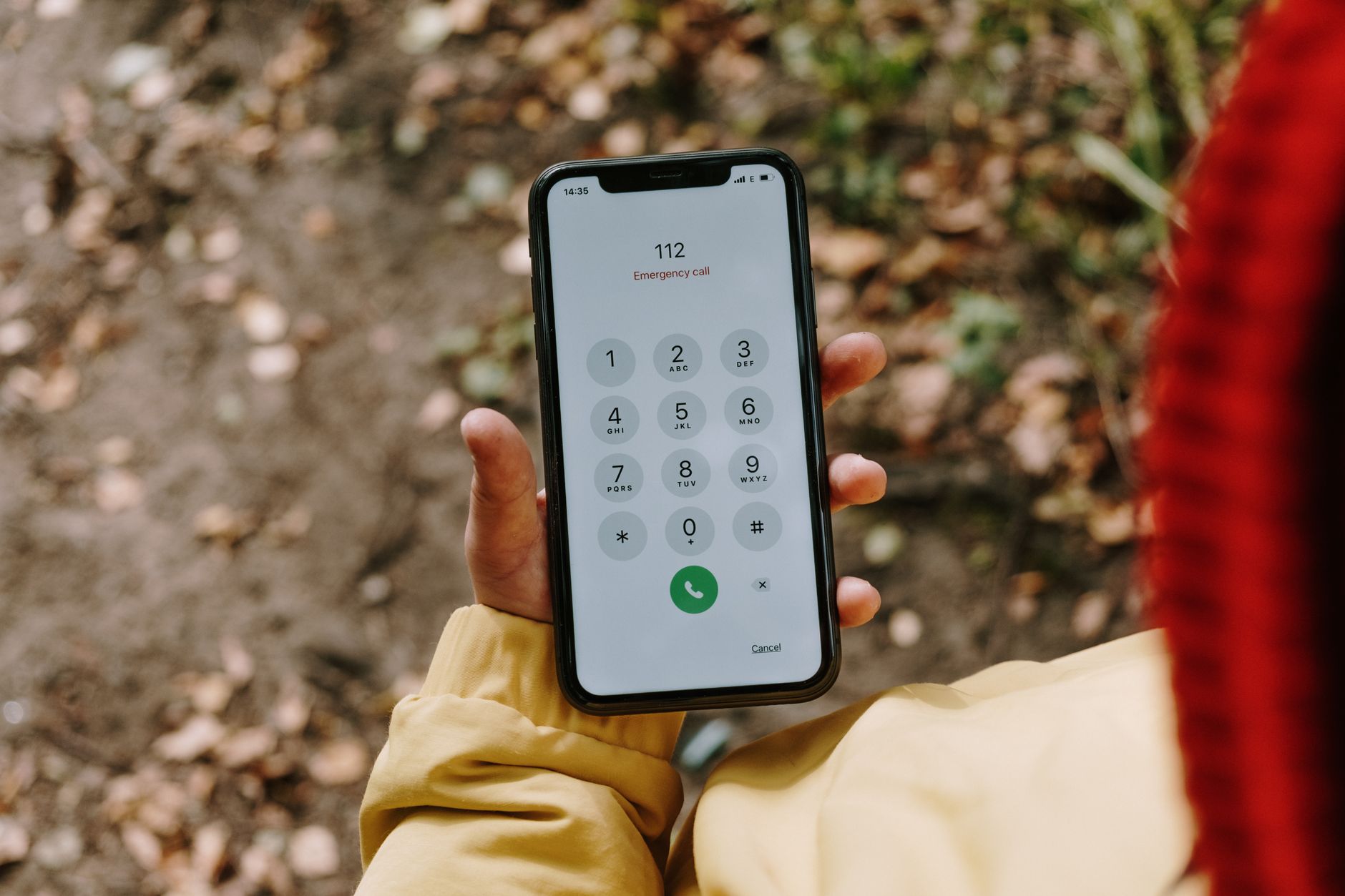 A woman holding a smartphone, ending a call and preparing to dial a saved contact.
