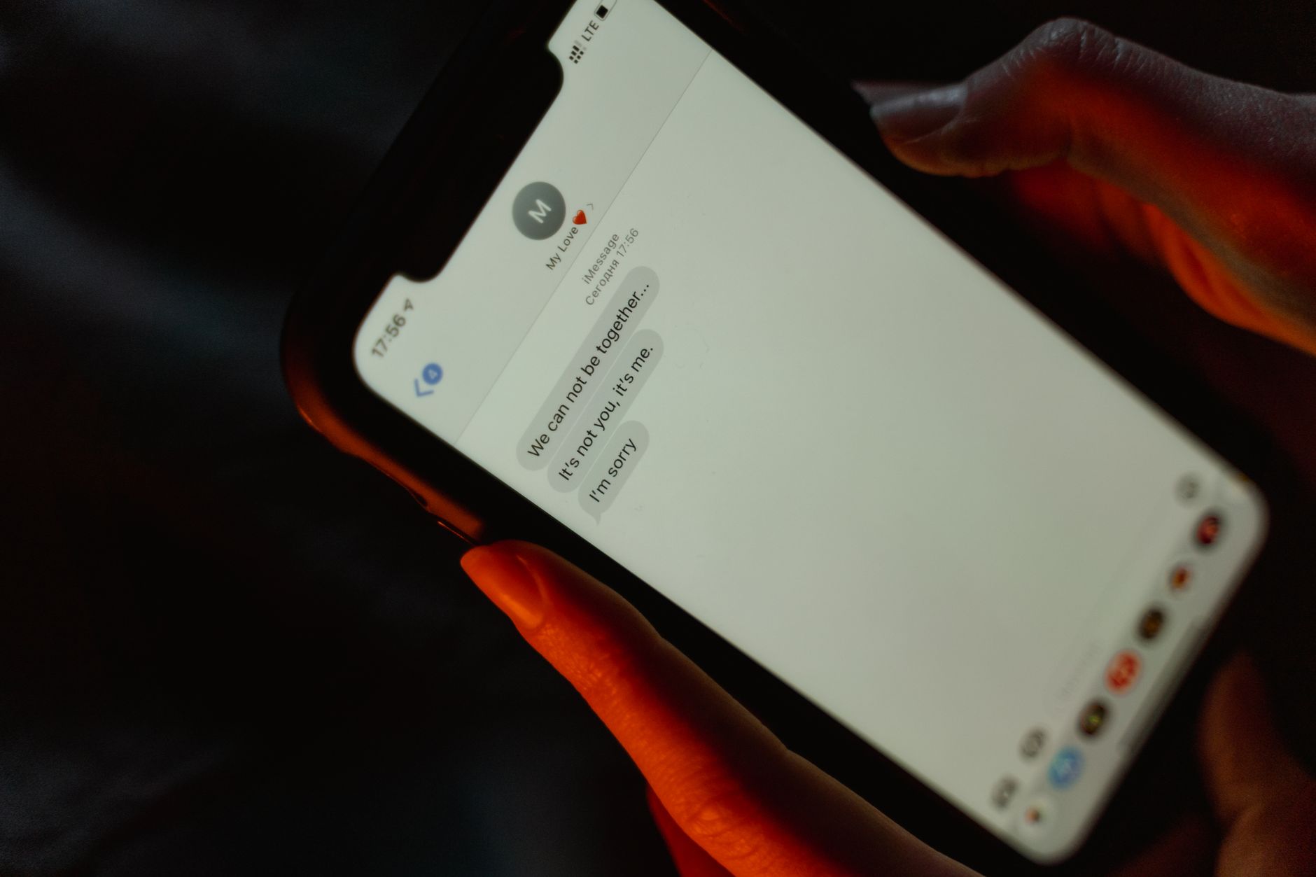 A person reads a suspicious text message on a smartphone with a serious expression.