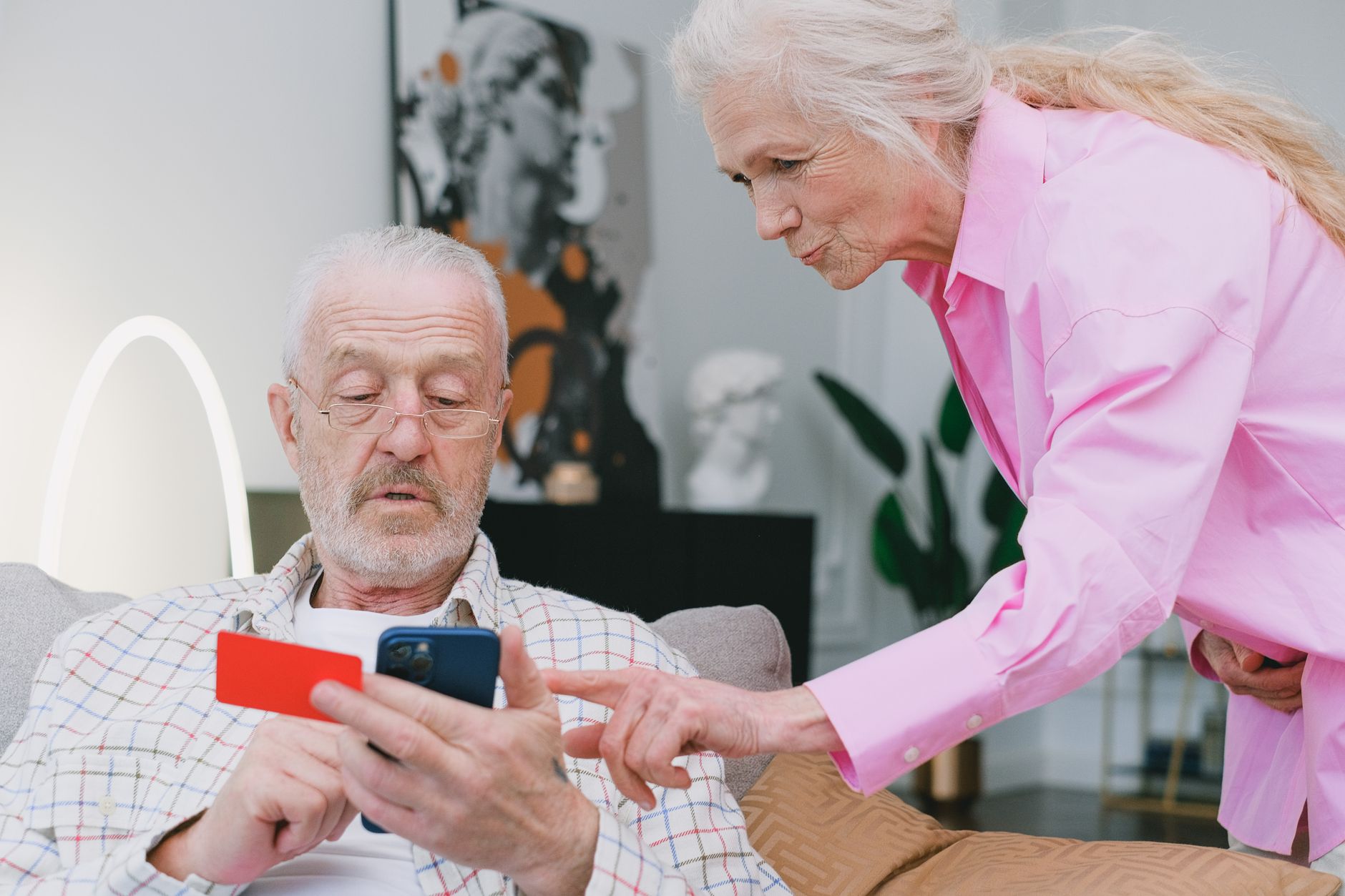 An adult child and an elderly parent looking at a bank statement together at a desk.