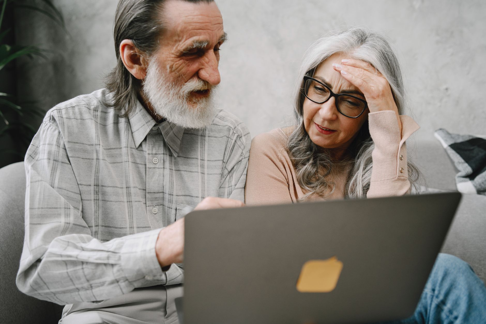 An older adult sitting beside an adult child while completing an online scam report on a laptop.